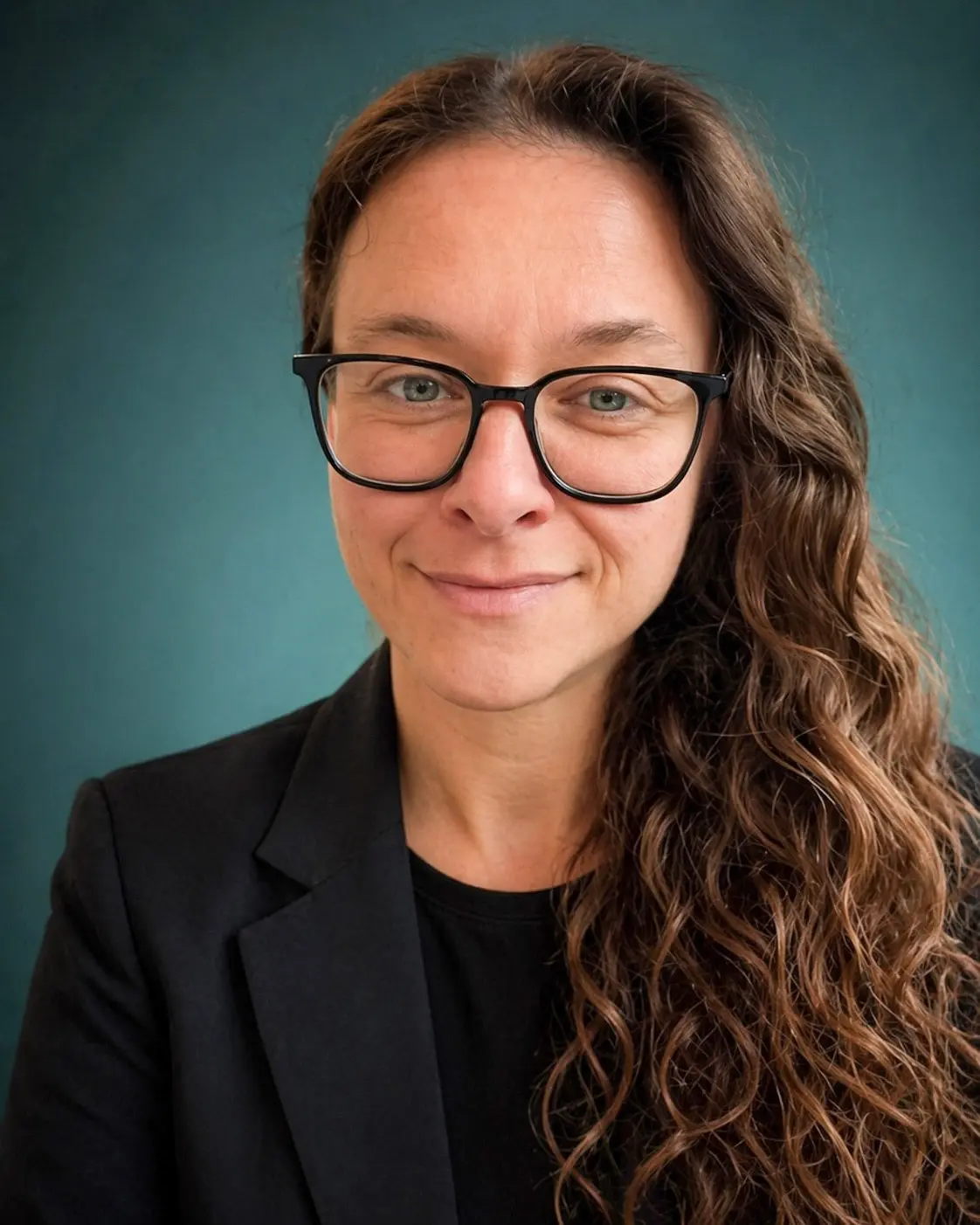 Headshot of Laurence Paquette smiling, wearing black-framed glasses and a dark blazer against a teal background