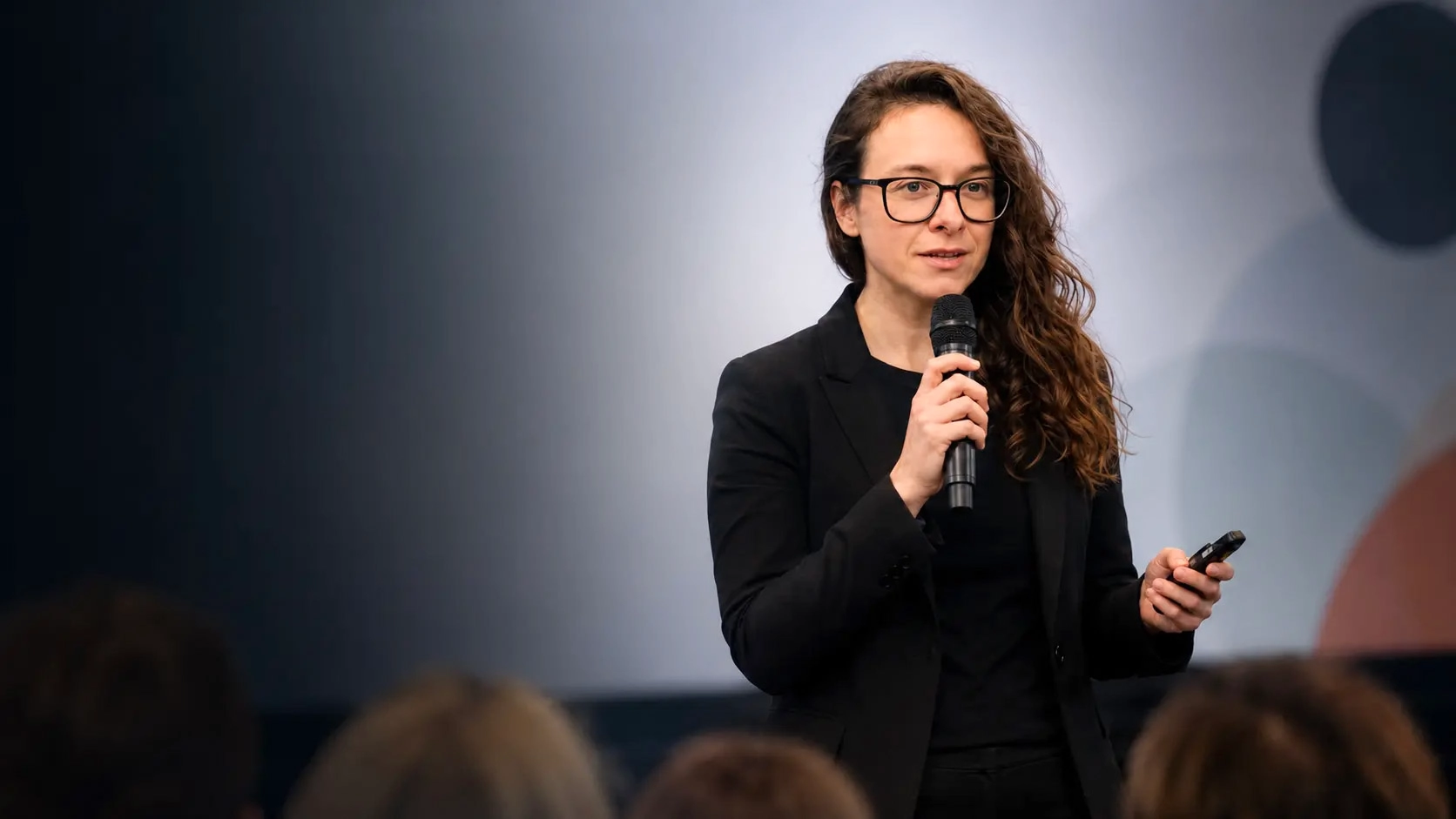 Laurence Paquette speaking on stage and holding a microphone during a keynote